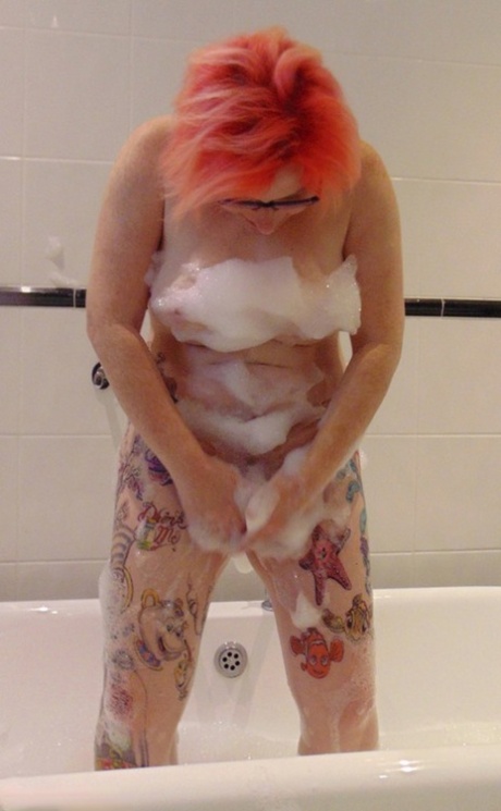 Mollie Foxxx, an amateur with a tattoo on her face, enjoys a bubble bath while wearing glasses.