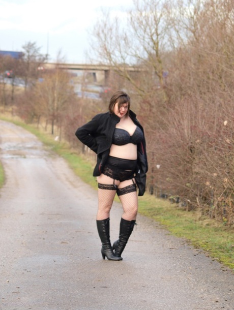 While walking a path, Roxy, who is overweight, exposes herself wearing black boots.