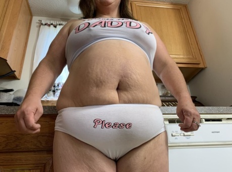 Sexy Nebbw, a middle-aged woman, exhibits her ample tits and buttocks in a kitchen.