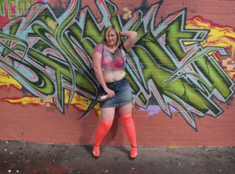 Samantha, an amateur plumper, exposes herself wearing knee-high nylon shirts in front of graffiti.