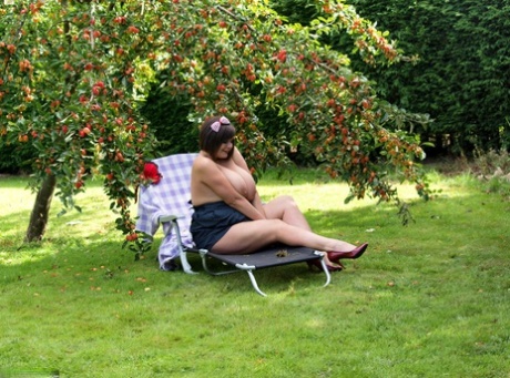 A naked Roxy bares her huge breasts and bald head beneath a fruit tree as an amateur.