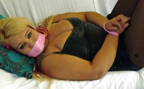 The woman with blonde fatty flesh is gagged and her wrists and ankles tied up.