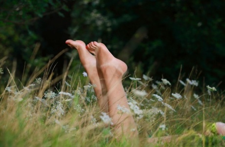 Hailey, the young girl, takes off in a field and dresses up on a blanket for nude poses.