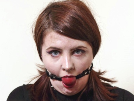 Tragically, Luna La Roux is tattooed with red hair and holds onto a string of straps while performing a ball gag.