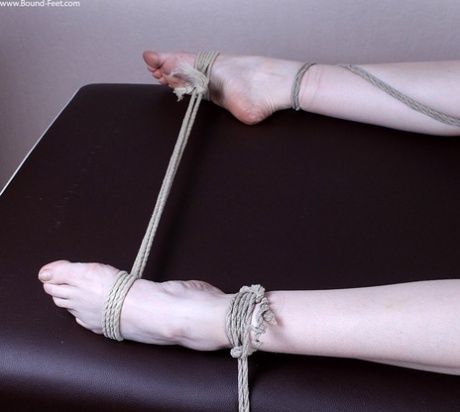 With a rope tied to the table, the thin redhead performs a ball gag while wearing tightrope on her panties.