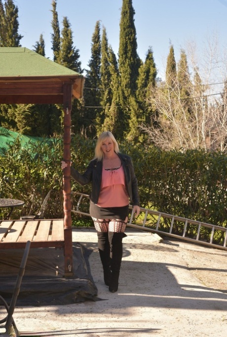 OTK boots: Overweight blonde Melody hides her breast in her OTK boots on a patio.