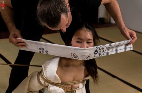 Flawless Meow, a Japanese woman, is gagged during Shibari practice.