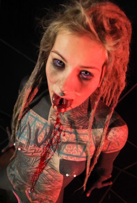 Полностью татуированная девушка Анускацц выплевывает кровь после того, как ей раскололи язык
