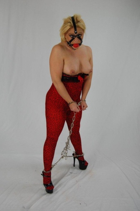 Until the end, the thick blonde is fastened in chains and forced to perform an awkward ball gag before sucking her cock.