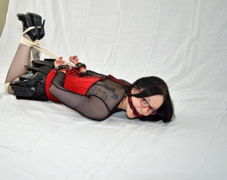 I see this creepy girl who is hogtiedied in her latex miniskirt and glasses.