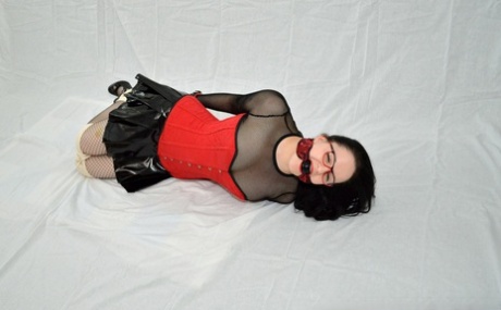 In a latex miniskirt and glasses, the geeky girl is seen with her hogtied.