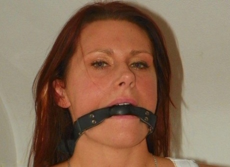Fully clothed, the amateur model is hogtied and gagged on a bed.