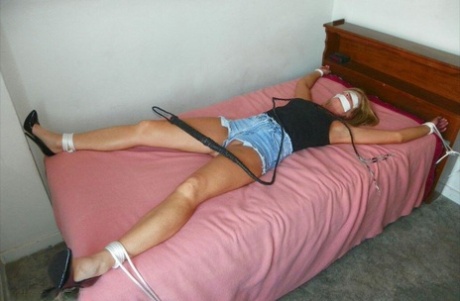 The women in revealing clothing are tied up with rope on a single bed, leaving them with gagged skin.