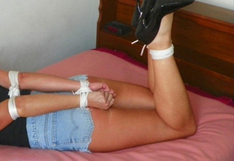 The women in revealing clothing are tied up with rope on a single bed, leaving them with gagged skin.