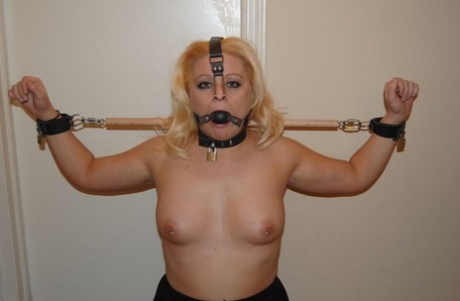 In a ball gag before a BJ, the topless blonde is released while being held back in a harness.