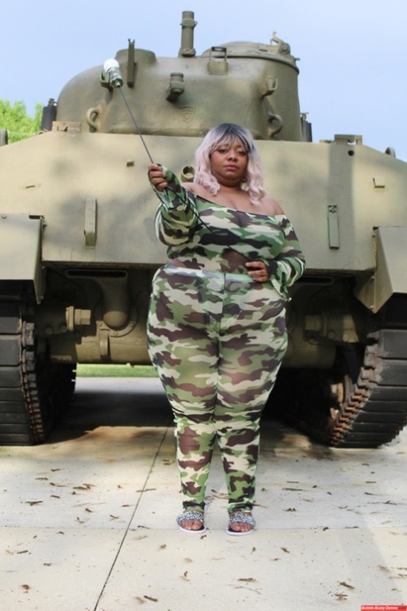 Carmelotto Rush, an affluent black woman, displays her tank on the opposite side with her thong-covered buttocks.