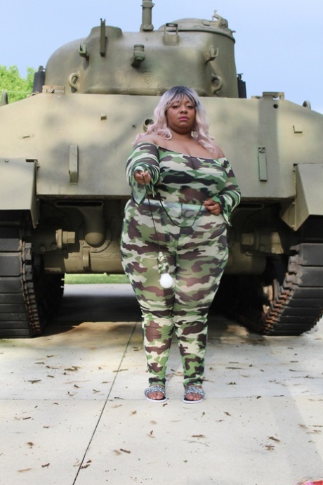 Carmelotto Rush, a black woman with a tattoo on her body, displays her tank-clad buttocks.