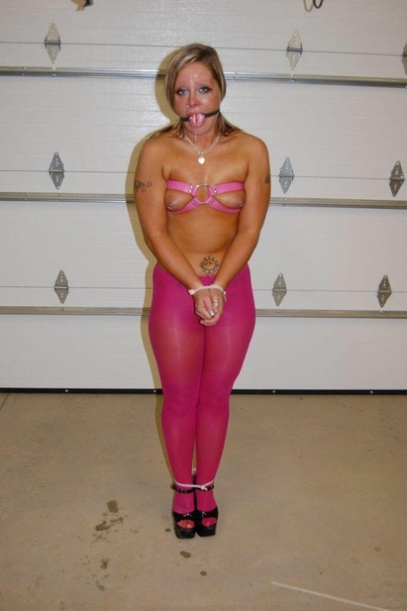 In pink pantyhose and heels, the dirty blonde performs a ball gag.