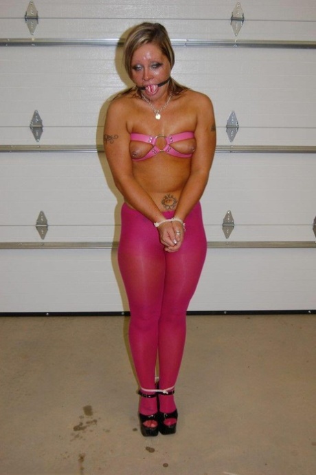 In pink pantyhose and high heels, the dirty blonde performs a ball gag.