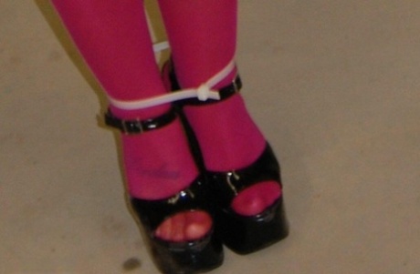 In pink pantyhose and high heels, the dirty blonde performs a ball gag.
