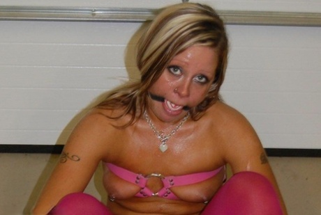 A dirty blonde wears pink pantyhose and heels as she performs a ball gag.