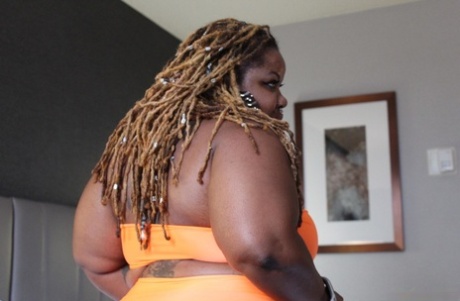 Atl Sexual Savage, an overweight ebony woman, exposes her tattooed body on a bed.