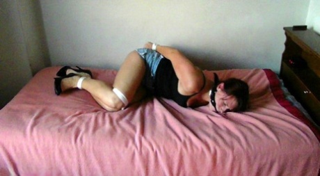 A Brunette woman was left on a bed with her legs tied up and gagged.