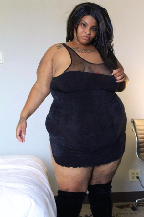 Ebony SSBBW Carmel Squirtz releases her large buttocks from a black dress.