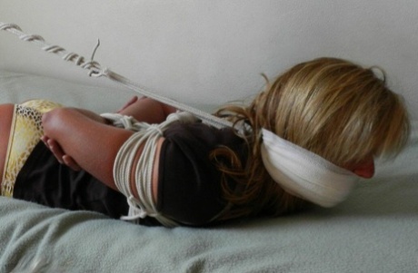 Despite being tied down on a bed, the blonde's barefoot is heavily gagged and held in place with rope.