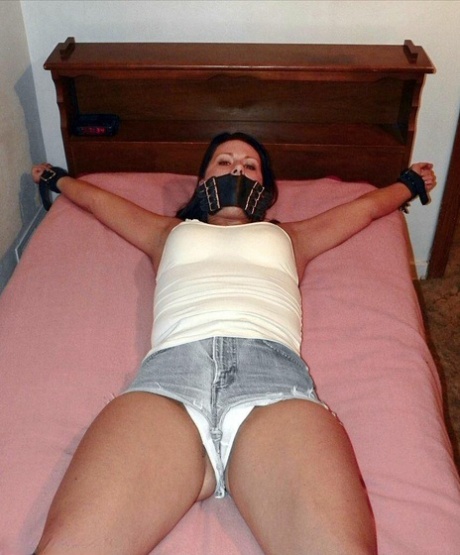 With her cleavage and boottied body, the solo girl is seen on a bed wearing denim cutoffs.