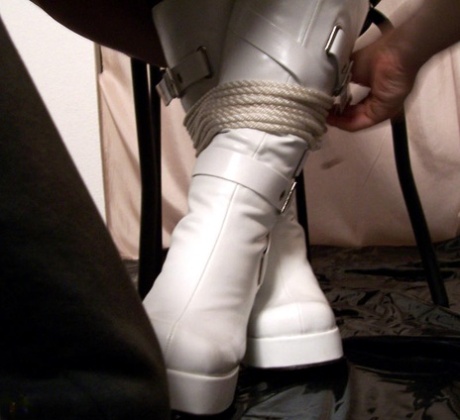 While wearing white boots, the solo model is tied up with rope.