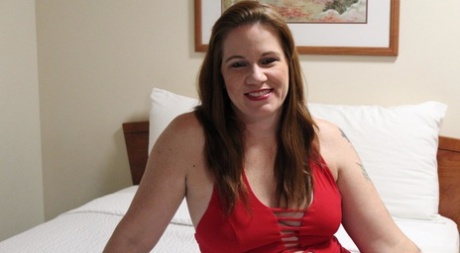 Ginger Reigh, the plump redhead, exhibits her painted toenails while dressed in a red dress.