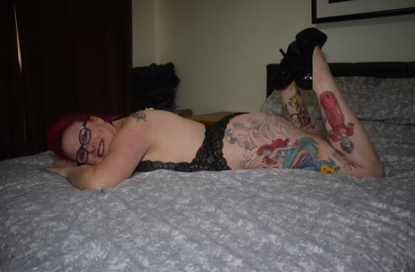 Tattooed redhead Mollie Foxxx models black lingerie with her glasses on