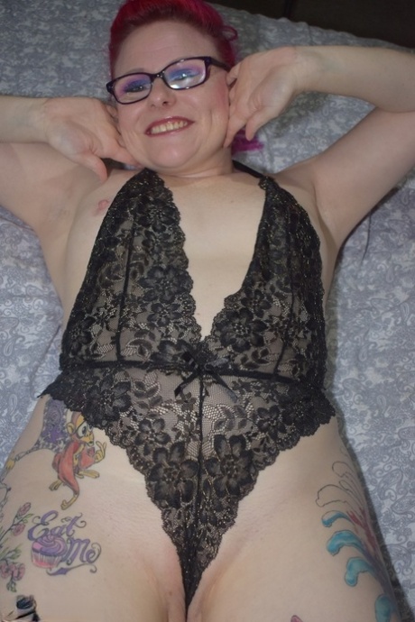 Tattooed redhead Mollie Foxxx models black lingerie with her glasses on