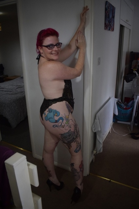 Tattooed redhead Mollie Foxxx models black lingerie with her glasses on