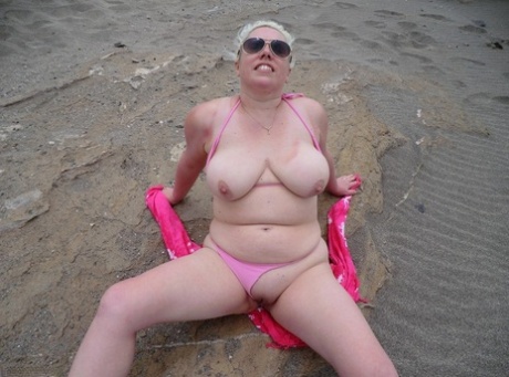 Old blonde Barby flaunts her chubby figure while lounging by the seaside as she exposes herself.