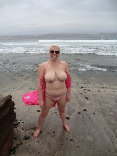 The seaside scene features Barby, a platinum blonde with an older physique, flaunting her plump figure.