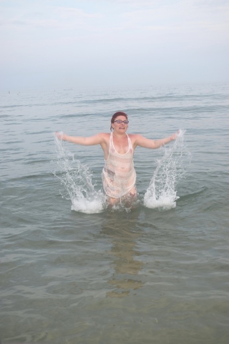 Before exposing herself, the tattooed redhead ventures out into the sea.