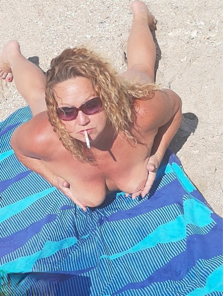 Debbie Delicious, a 20-year-old volunteer at the local beach club, enjoys smoking in the nude while relaxing on the shore.