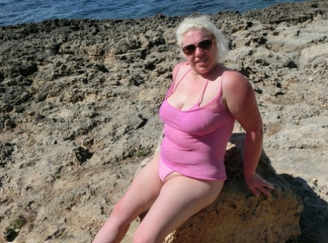 Close to the ocean, Chubby older blonde Barby goes naked in shades of color.