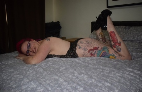 Tattooed amateur Mollie Foxxx poses in black lingerie while wearing glasses.