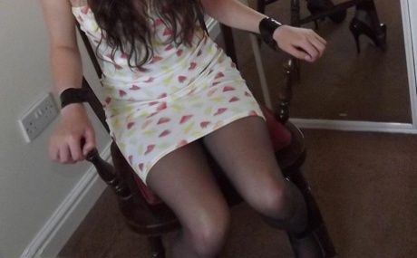 The girl Tamara, dressed in clothes, is unable to move and appears to be gagged and restrained in a chair while staring at a mirror.