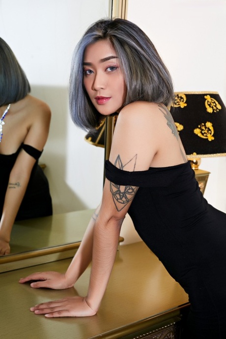 An Asian babe with tattoos sheds her small tits and pussy while wearing a small black dress.