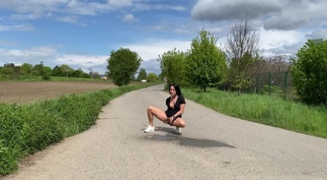 Brunette female Lexi Dona pees on a paved road in the countryside