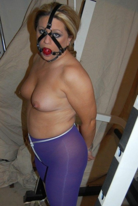 Sporting a ball gag while unclothed and wearing purple pantyhose, the blonde with hair is quite plump.