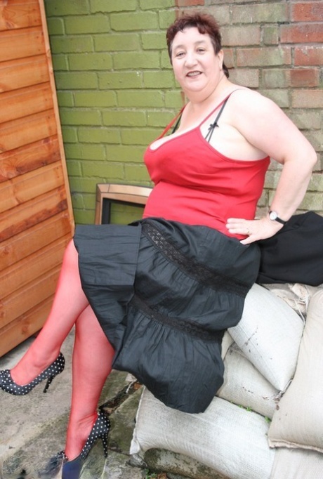 Older amateur Kinky Carol has short hair and is wearing stockings in red.