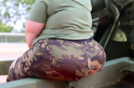 Models of Obese Amateur deity Goddess Pear are used in a SFW photo shoot wearing camouflage and an artillery gun.
