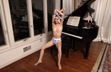 Blonde teen Jessica Marie sits at a piano before playing with toys in the nude