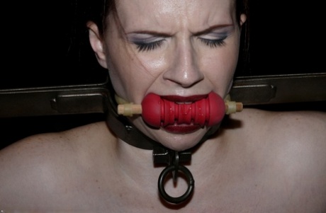 Claire Adams displays red lips in a brutal bondage scene.