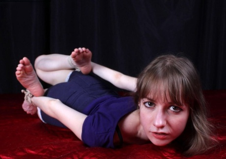 After being clothed, Agnes finds herself lying face down with her ankles tied around her wrists.